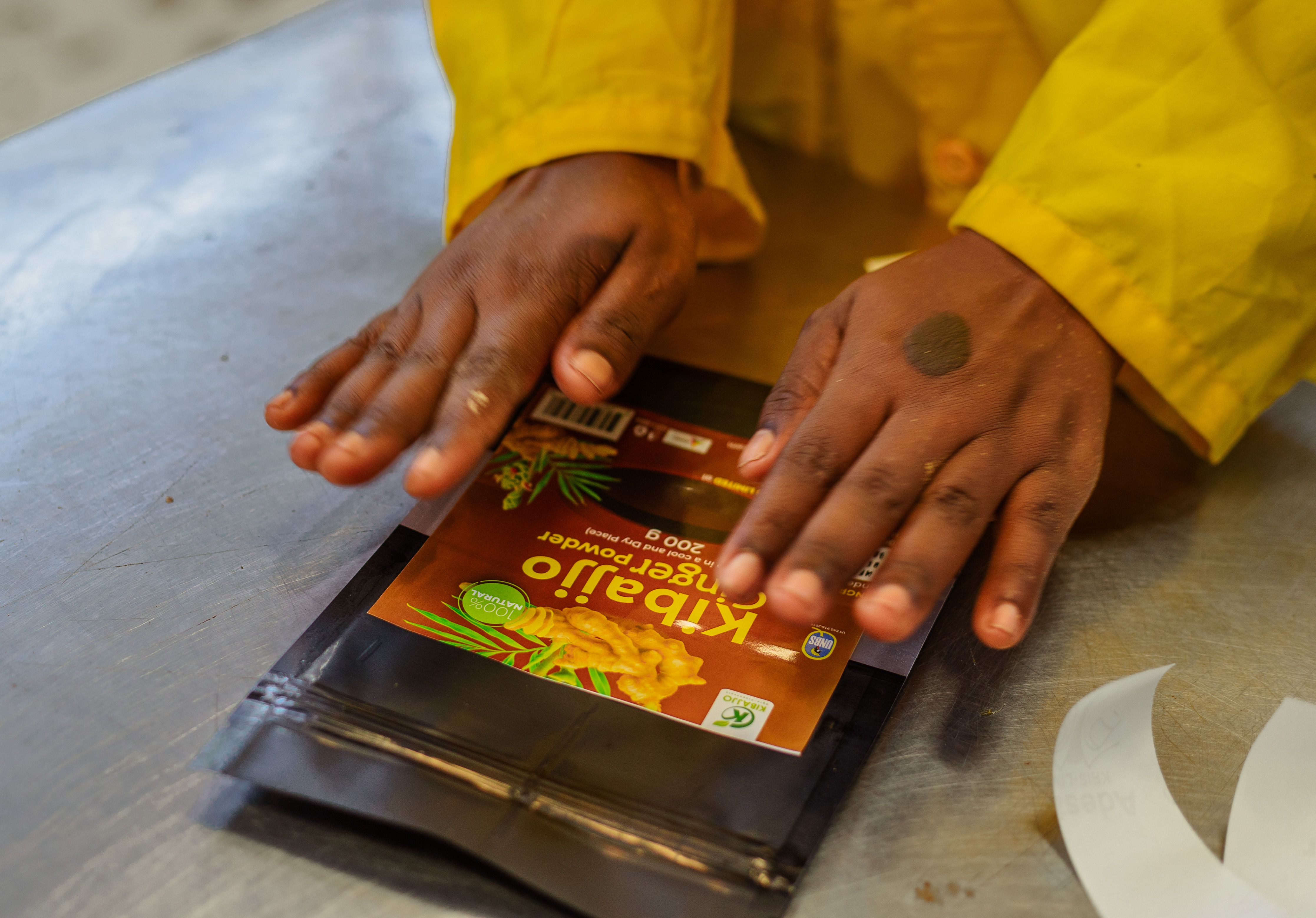 A Kibajjo team member sealing a ginger powder pouch