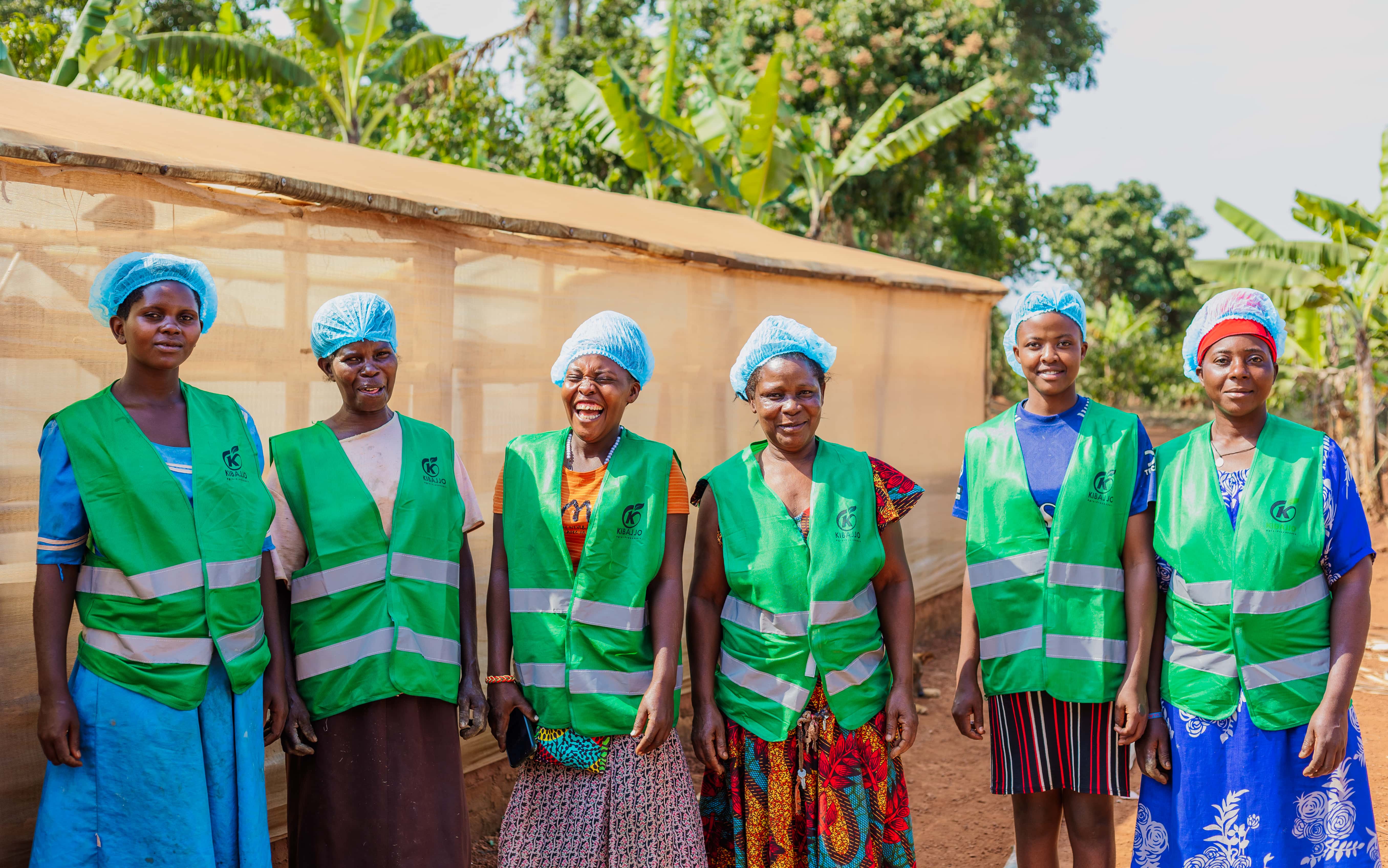 Kibajjo processing team standing together beside the solar dryer