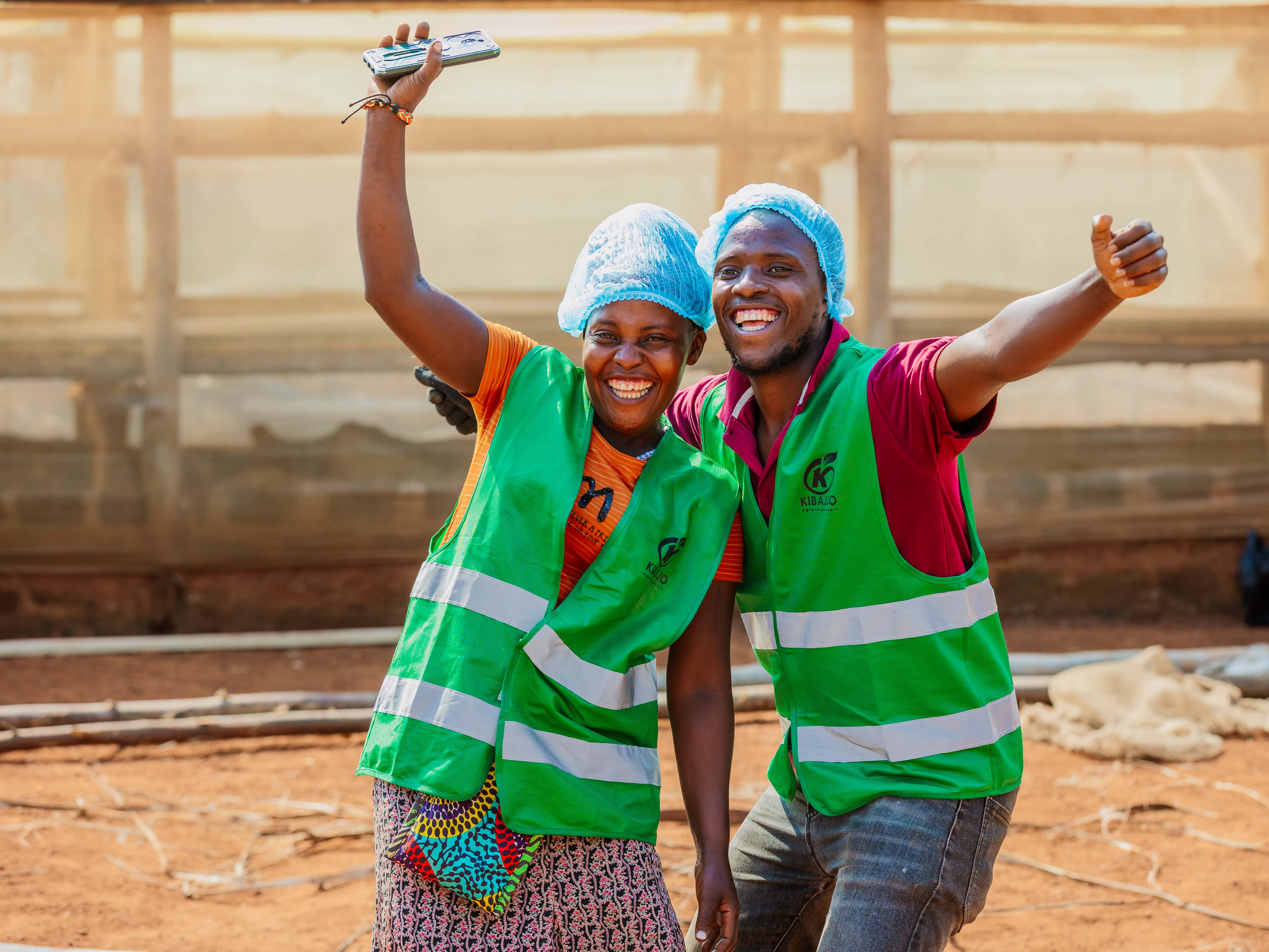 Two Kibajjo team members sharing a cheerful moment beside the dryer
